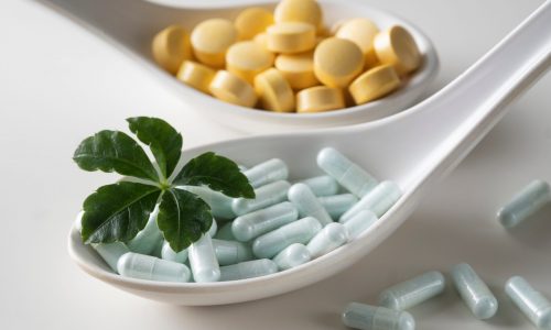 Spoons filled with different tablets with green leaf on a white Spoons filled with different tablets with green leaf on a white